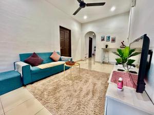 a living room with a blue couch and a table at Cozy 288 Entire 3 bedroom House @ Alma Bukit Mertajam in Bukit Mertajam