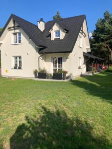 a white house with a black roof at Agroturystyka u Sylwii in Majdan Sopocki