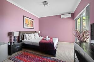 Lilli PilliにあるWaterfront Ensuite Queen Room - Luxury & Comfort Place in Caringbah Southの紫の壁のベッドルーム、ベッド1台、テレビが備わります。