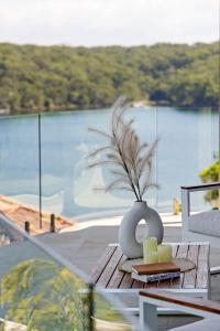 a vase with candles on a table with a view of the water at Tranquil Waterfront Single Room in Caringbah South - Stunning Views - Shared Bathroom in Lilli Pilli