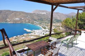 a balcony with a table and chairs and a view of a beach at Pano Gitonia in Aegiali