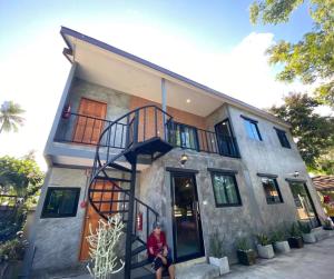 a person sitting in front of a house at Bigland Homestay in Bang Sare