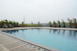a large swimming pool with benches and tables in a building at Comfort 2BR at Tree Park City BSD Apartment By Travelio in Tangerang