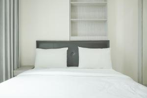 a bed with white sheets and pillows in a bedroom at Comfort 2BR at Tree Park City BSD Apartment By Travelio in Tangerang