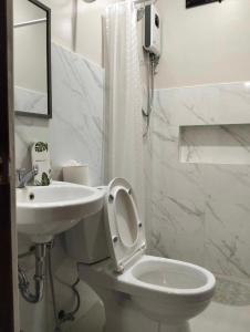 プエルト・プリンセサにあるJMorino Pension Houseのトイレと洗面台を備えた白いバスルーム