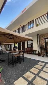 プエルト・プリンセサにあるJMorino Pension Houseの建物の前にテーブルと大きな傘付きのパティオ