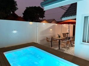 Casa con piscina y mesa con sombrilla en liwei cozy pool villa, en Pattaya South