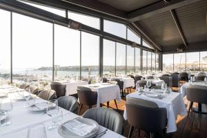 a restaurant with white tables and chairs and windows at Wyndham Grand Istanbul Kalamış Marina Hotel in Istanbul