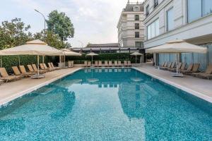 a swimming pool with chairs and umbrellas next to a building at Wyndham Grand Istanbul Kalamış Marina Hotel in Istanbul