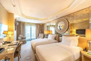 a hotel room with two beds and a desk at Wyndham Grand Istanbul Kalamış Marina Hotel in Istanbul