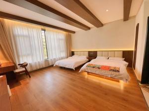 two beds in a large room with wooden floors at Kashgar QiuGe Homestay in Kashgar