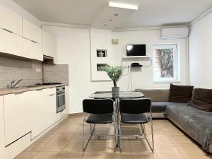 a kitchen and living room with a table and a couch at NMG APARTMAN - Péter utca in Pécs
