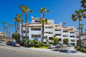 a large white building with palm trees in front of it at San Clemente Cove Resort in San Clemente