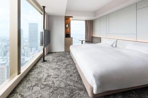 a bedroom with a large white bed and large windows at Hotel Hankyu GRAN RESPIRE OSAKA in Osaka +43 photos