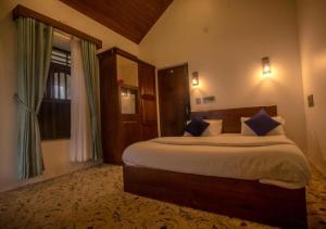 a bedroom with a large bed with blue pillows at Anudhyana Premium Private Stone Villa Vagamon by VOYE HOMES in Vagamon