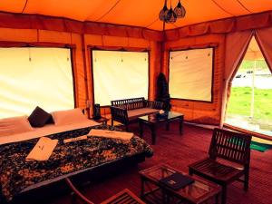 a bedroom with two beds and chairs in a tent at Sheenwoods Riverside Resort & Spa in Sonāmarg