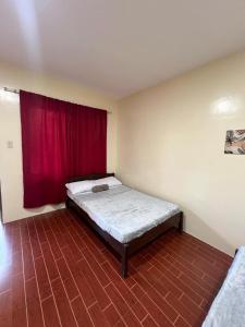 ein Schlafzimmer mit einem Bett mit einem roten Vorhang in der Unterkunft Apt 5 - Christmark Pension in El Nido