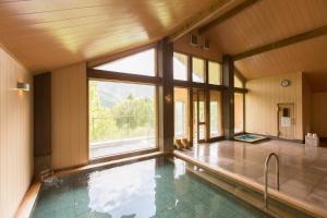 a swimming pool with a large window in a house at Izumigo AMBIENT Azumino Hotel in Azumino