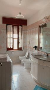 a bathroom with a sink and a toilet and a mirror at Il Bouganville in Oristano