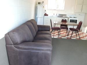 a brown leather couch in a kitchen with a table at Maple Lodge Motel in Matamata