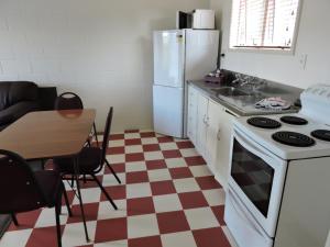 a kitchen with a white refrigerator and a table at Maple Lodge Motel in Matamata