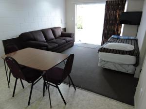 a living room with a couch and a table and a bed at Maple Lodge Motel in Matamata