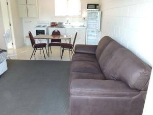 a living room with a brown couch and a table at Maple Lodge Motel in Matamata