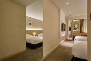 a hotel room with two beds and a mirror at Summit Hotel Seoul Dongdaemun in Seoul
