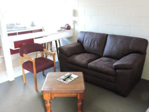 uma sala de estar com um sofá, uma mesa e uma cadeira em Maple Lodge Motel em Matamata