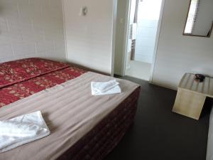 a hotel room with a bed with two towels on it at Maple Lodge Motel in Matamata