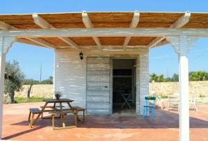 a patio with a table and a wooden pergola at Country Salenthouse in Marina di Mancaversa