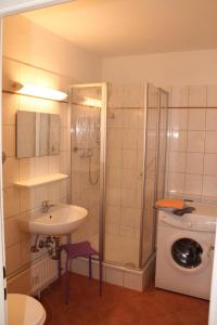 ein Badezimmer mit einem Waschbecken, einer Dusche und einer Waschmaschine in der Unterkunft Ferienappartement E226 für 2-4 Personen an der Ostsee in Brasilien