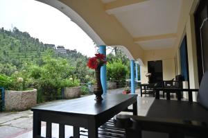 a vase with a red flower on a table on a balcony at Daaruka vane eco resort in Jageshwar