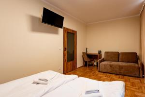 a bedroom with a bed and a couch and a television at Gwiazda Tatr - ośrodek rekolekcyjno - wypoczynkowy in Zakopane