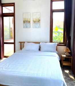 Un dormitorio con una gran cama blanca con dos ventanas. en Vang's Homestay - Huế, en Ấp Long Hồ Hạ