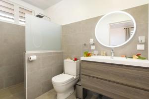 a bathroom with a toilet and a sink and a mirror at Villa Hana in Maharepa +5 photos