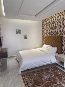 Un dormitorio con una cama grande con cabecero marrón. en Savvy Residences, en Abuja