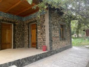 a stone house with a red bucket on the porch at Yaxshigulhomestay in Yukary-Ukhum +17 photos
