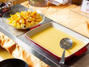a tray of yellow sauce and a bowl of fruit at Hotel Wing International Premium Osaka-Shinsekai in Osaka
