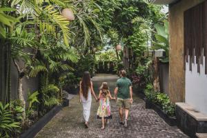 eine Familie, die durch einen tropischen Garten geht in der Unterkunft Canggu Circle Villa by Ini Vie Hospitality in Canggu + 41 Fotos