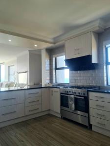 a kitchen with white cabinets and a stove top oven at View At The Bay in Mossel Bay