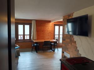 a living room with a table and a television on a wall at Bilocale Centro Valtournenche in Valtournenche