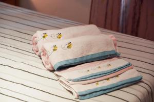una pila di asciugamani con api su un letto di Domàtio Melissa Summer ad Alghero