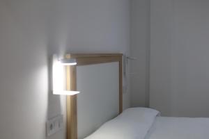 a room with two beds and a light on the wall at Hospedium GL Andújar Boutique in Andújar