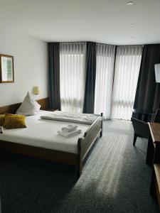 a hotel room with a bed and a chair at Landhotel Sonnenbühl in Sonnenbühl