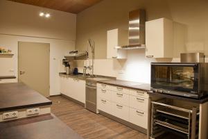 eine große Küche mit weißen Schränken und Küchengeräten aus Edelstahl in der Unterkunft Haus Gipfelstürmer Harz in Braunlage