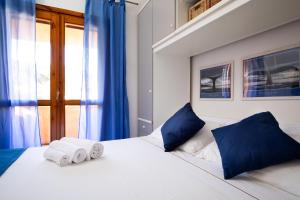 Un dormitorio con una gran cama blanca con almohadas azules. en Homey Experience - Attic Panorama, en La Maddalena