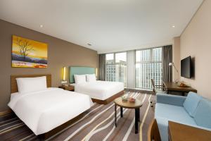 una habitación de hotel con dos camas y un sofá en Holiday Inn Express Hangzhou Huanglong, en Hangzhou