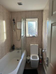 a bathroom with a tub and a toilet and a window at Cosy Home In Sheffield in Handsworth