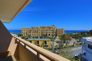 een balkon met uitzicht op een gebouw en de oceaan bij City Center Hotel in Rhodos-stad